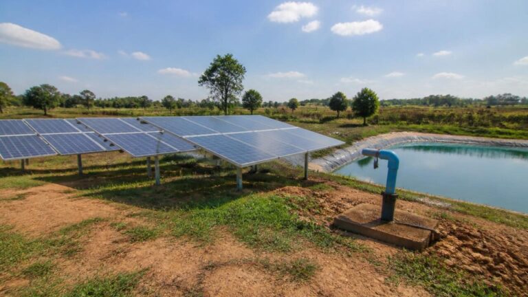 Painéis solares instalados em área rural com tanque de água ao fundo