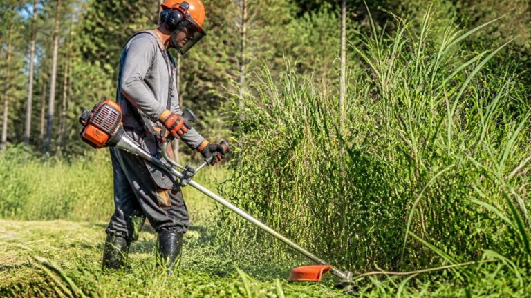 Roçadeira em uso cortando vegetação em uma área rural com operador usando equipamento de proteção