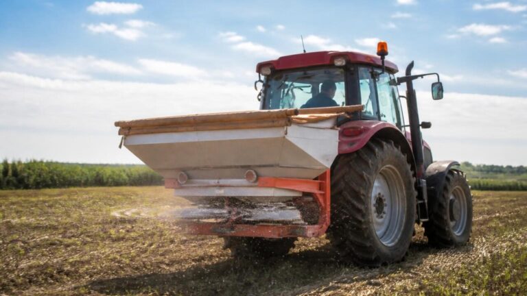 Distribuidor de fertilizantes em operação aplicando grânulos uniformemente em um campo
