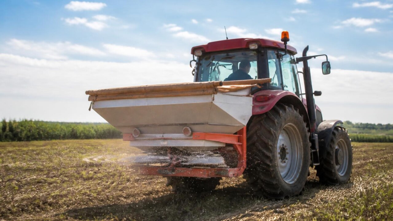 Distribuidor de fertilizantes em operação aplicando grânulos uniformemente em um campo